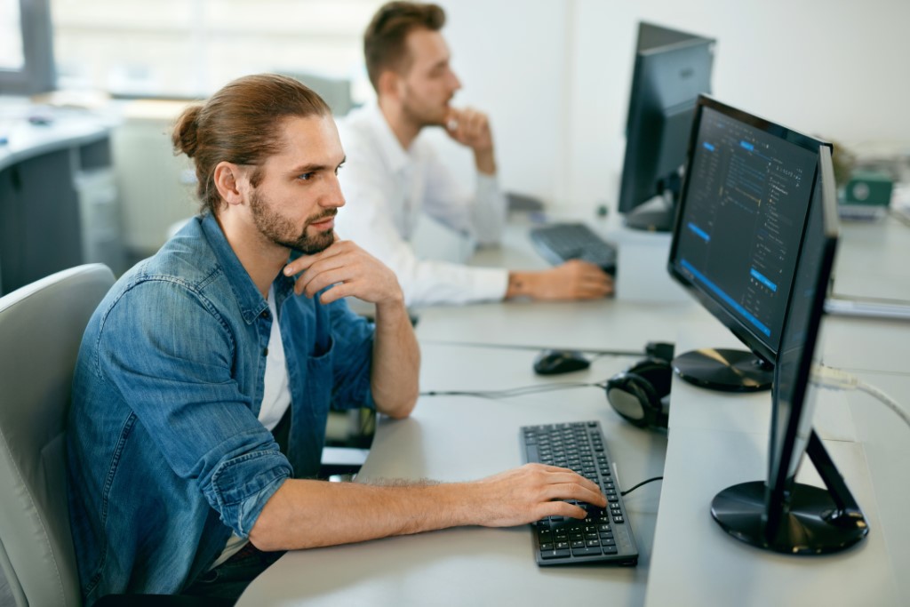 Zwei IT-Mitarbeiter sitzen vor Ihren PCs.